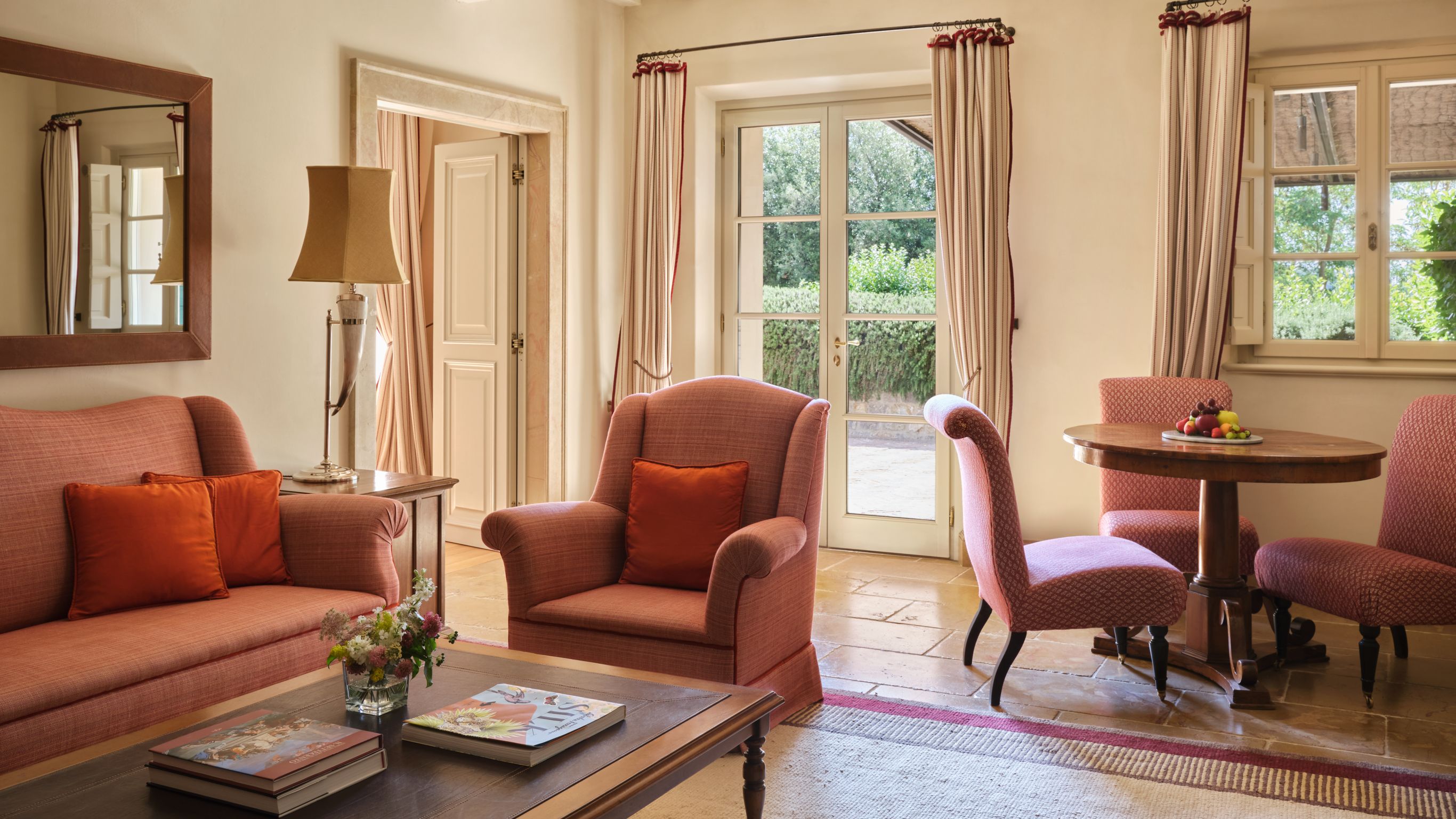 Living room in a Tuscany hotel suite with sofa, armchairs, table, lamp, and glass doors